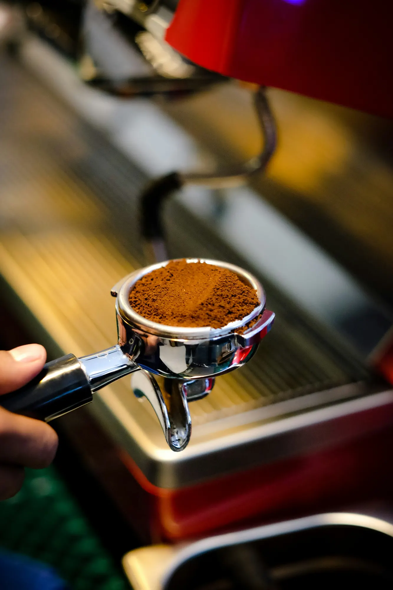 Ο barista κρατά το πορταφίλτρο με φρεσκοαλεσμένο καφέ