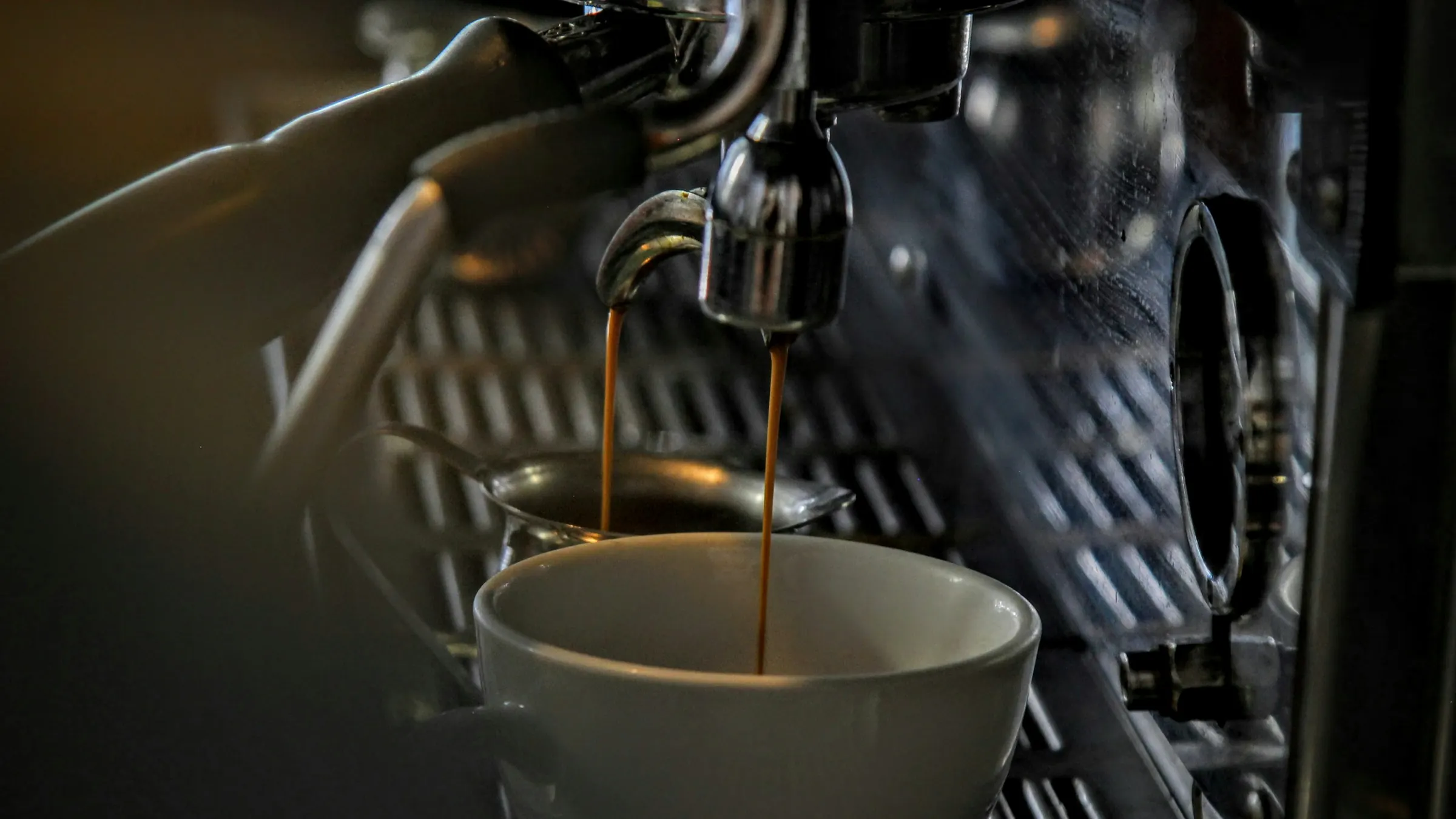 Espresso pouring from a machine into a porcelain cup